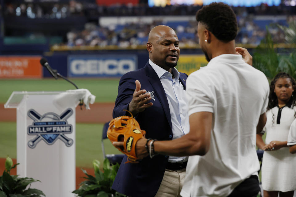 Former Tampa Bay Rays player Carl Crawford, center, embraces his son Justin, front right, after throwing out a ceremonial first pitch during his Rays Hall of Fame induction ceremony prior to a baseball game against the New York Yankees, Saturday, Aug. 26, 2023 in St. Petersburg, Fla. (AP Photo/Scott Audette)