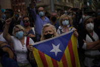A woman holds a Catalonia independence flag as people take part in a protest outside the Italian consulate in support of former Catalan leader Carles Puigdemont in Barcelona, Spain, Friday, Sept. 24, 2021. Puigdemont, who fled Spain after a failed secession bid for the northeastern region in 2017, was detained Thursday in Sardinia, Italy, his lawyer said. Puigdemont, who lives in Belgium and now holds a seat in the European Parliament, has been fighting extradition to Spain, which accused him and other Catalan independence leaders of sedition. (AP Photo/Joan Mateu)