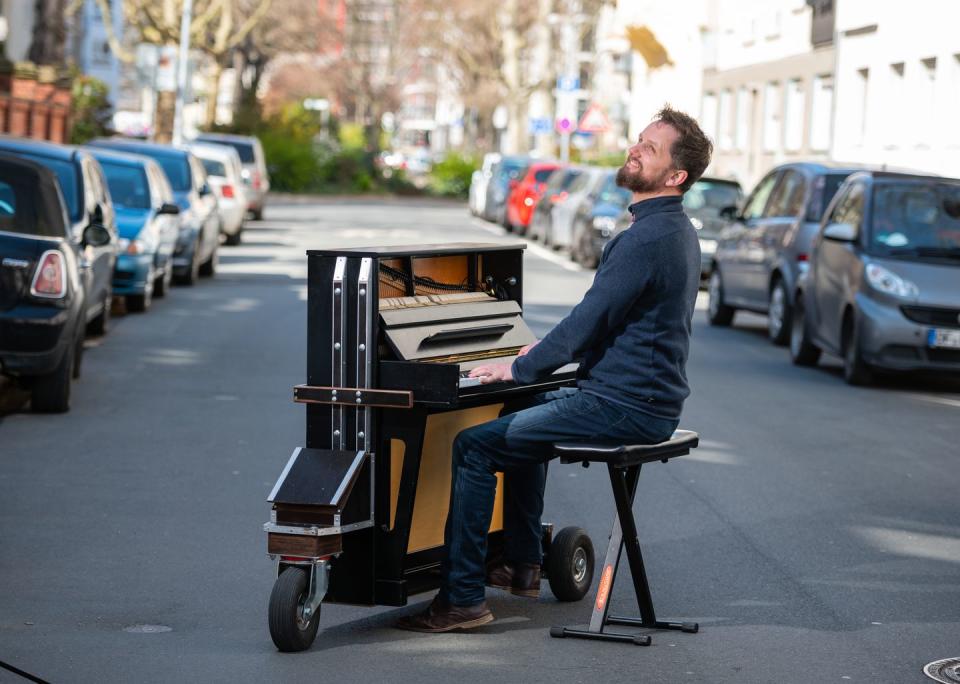 <p>A pianist in Mainz, Germany takes his rolling piano around to play for quarantined residents during the Coronavirus pandemic in March 2020.</p>
