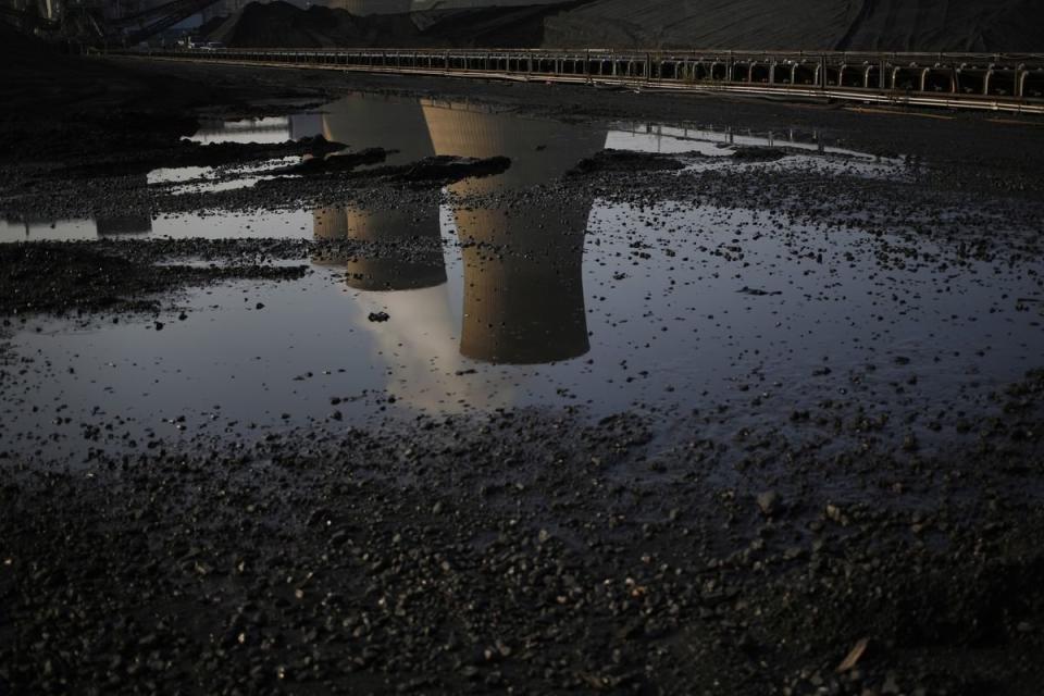 Cooling towers are reflected in a puddle at the American Electric Power Company's coal-fired John E. Amos Power Plant in Winfield, West Virginia. (Bloomberg)