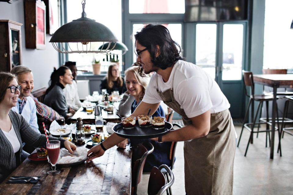 Waiter serving food to customers at a restaurant table