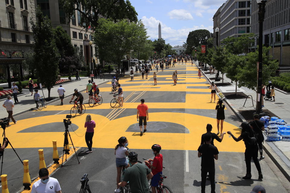 With the Washington Monument in the background people walk on the street leading to the White House after the words Black Lives Matter were painted on it by city workers and activists Friday, June 5, 2020, in Washington. (AP Photo/Manuel Balce Ceneta)