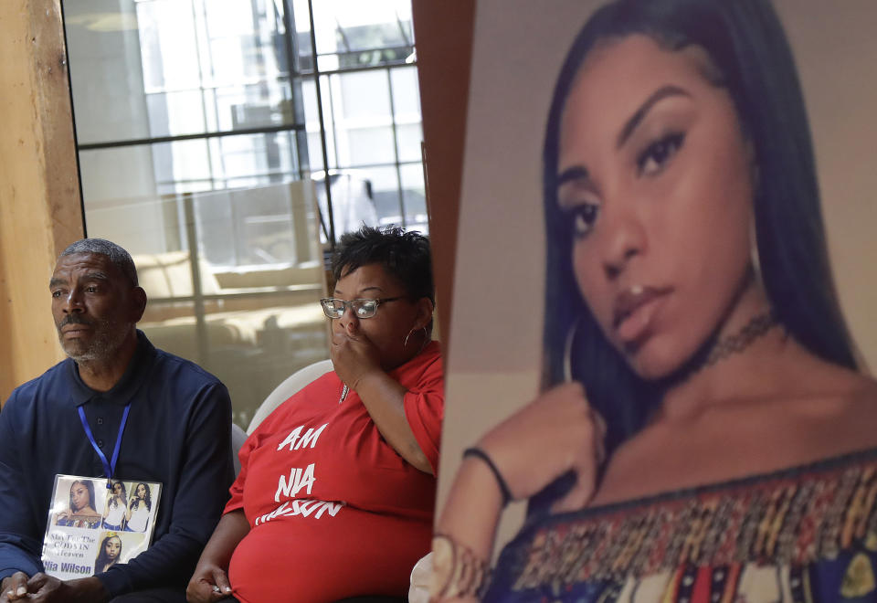 FILE - In this Aug. 17, 2018, file photo, a photo of victim Nia Wilson, right, is displayed at a news conference as her father Ansar El Muhammad, left, and her mother Alicia Grayson listen during a news conference in San Francisco. Prosecutors have special circumstances charges against John Cowell who was arrested in the killing of Wilson at a train station in Northern California. Alameda County District Attorney's Office on Wednesday, Aug. 22, 2018, added the special circumstances enhancement of "lying in wait" to Cowell's complaint, allegations that could make him eligible for the death penalty. (AP Photo/Jeff Chiu, File)