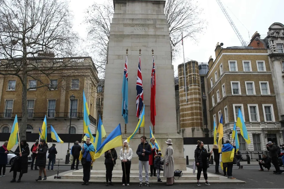 People wave the Ukraine national flag as they stand by the Cenotaph memorial in central London on the one year anniversary since the invasion of Ukraine by Russia (AFP via Getty Images)