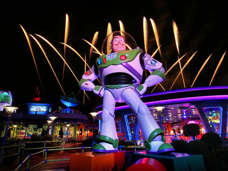 A large statue of buzz lightyear with fireworks behind him at disney world