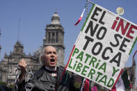 An Anti-government demonstrator dressed as independence hero Miguel Hidalgo, holds a sign that reads in Spanish "Do not touch INE, Motherland and Freedom," during a march against recent reforms pushed by President Andres Manuel Lopez Obrador to the country's electoral law that they say threaten democracy, in Mexico City's main square, The Zocalo, Sunday, Feb. 26, 2023. (AP Photo/Fernando Llano)