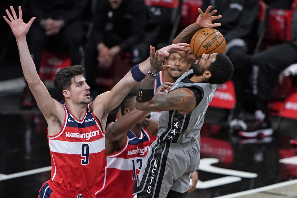 Washington Wizards forward Deni Avdija, left, tips the ball from Brooklyn Nets guard Kyrie Irving, right, during the first quarter of an NBA basketball game Sunday, Jan. 3, 2021, in New York. (AP Photo/Kathy Willens)