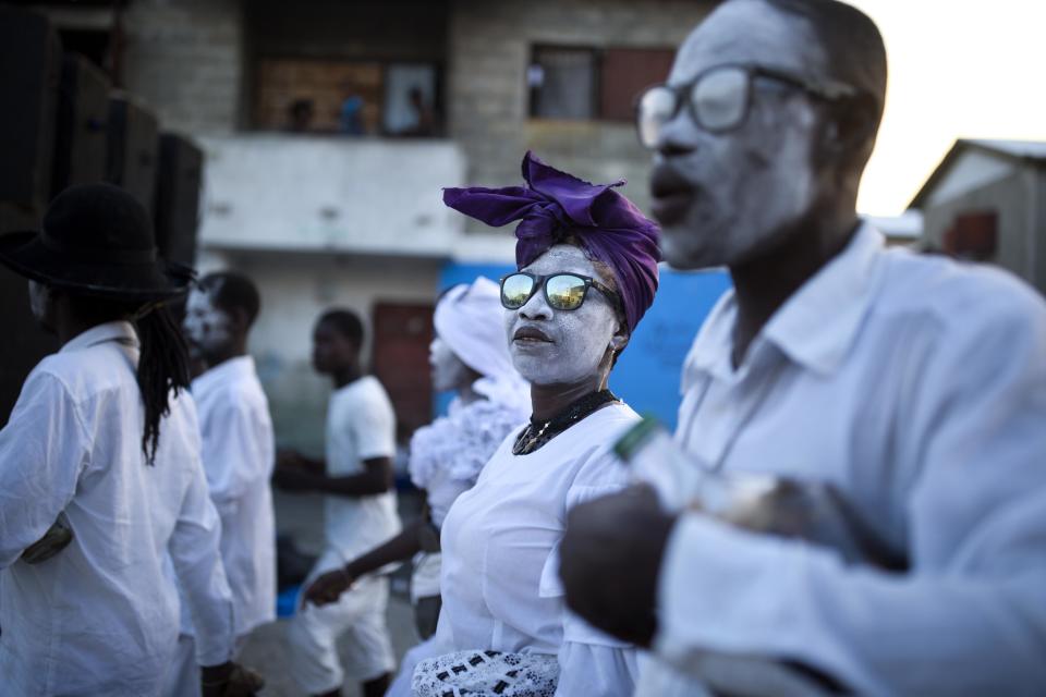 In this Nov. 1, 2018 photo, voodoo believers thought to be possessed with Gede's spirit walk in the middle of the street during the annual Voodoo festival Fete Gede at Cite Soleil Cemetery in Port-au-Prince, Haiti. During the festival, believers dress up as Gede spirits known as “Loas” and say they become possessed by those who hear their prayers and provide favors to members of their congregation. (AP Photo/Dieu Nalio Chery)