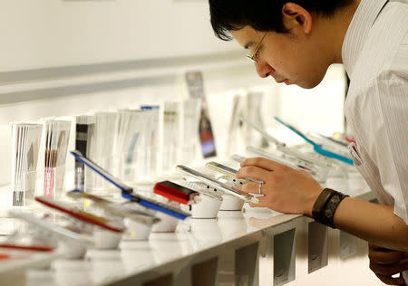 A man looks at mobile phones at the SoftBank Group Corp's headquarters in Tokyo, June 30, 2016. REUTERS/Toru Hanai/File Photo