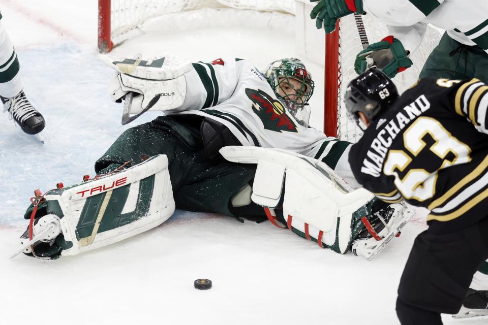 Minnesota Wild's Marc-Andre Fleury sprawls on the ice as Boston Bruins' Brad Marchand (63) goes for the puck during the third period of an NHL hockey game, Tuesday, Dec. 19, 2023, in Boston. (AP Photo/Michael Dwyer)