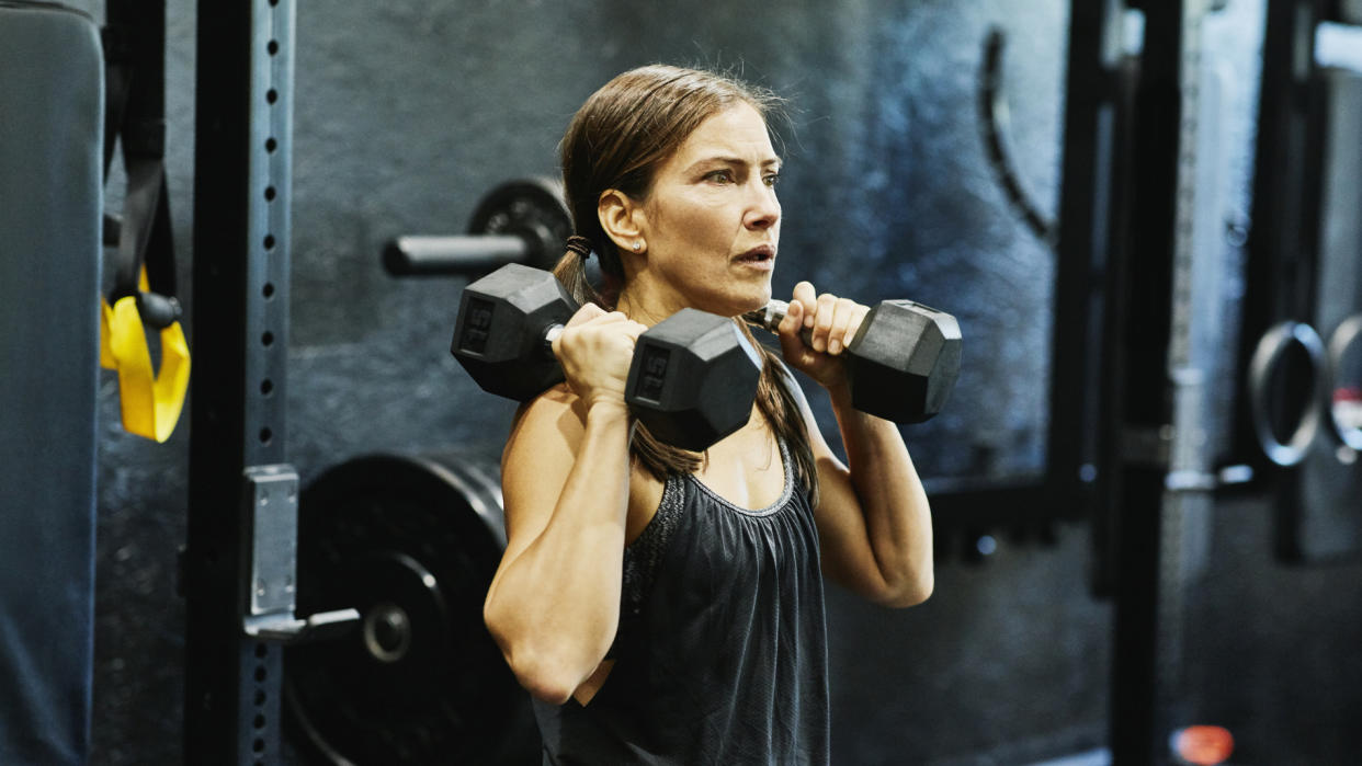  A 40-year old woman doing a dumbbell workout in the gym. 