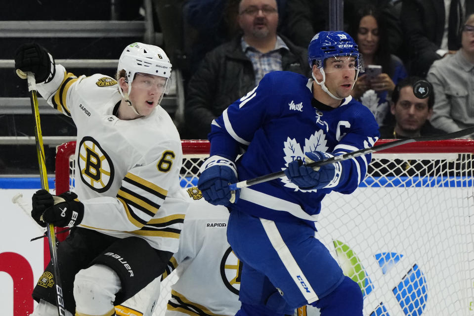 Toronto Maple Leafs center John Tavares (91) tries to control the puck as Boston Bruins defenseman Mason Lohrei (6) defends during first-period NHL hockey game action in Toronto, Monday, March 4, 2024. (Frank Gunn/The Canadian Press via AP)