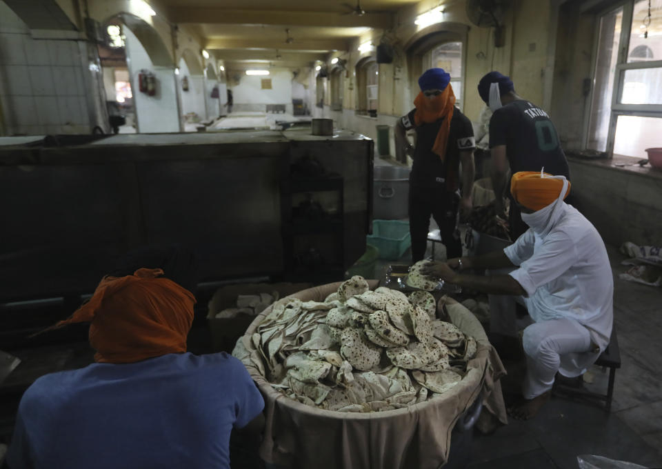 Sikh volunteers take out cooked chapatis, thin unleavened breads, from a machine in the kitchen hall of the Bangla Sahib Gurdwara in New Delhi, India, Sunday, May 10, 2020. The Bangla Sahib Gurdwara has remained open through wars and plagues, serving thousands of people simple vegetarian food. During India's ongoing coronavirus lockdown about four dozen men have kept the temple's kitchen open, cooking up to 100,000 meals a day that the New Delhi government distributes at shelters and drop-off points throughout the city. (AP Photo/Manish Swarup)