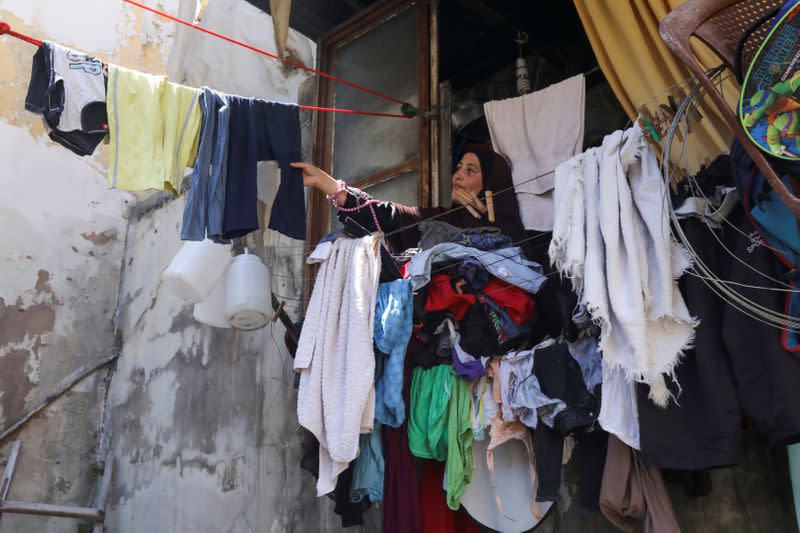 Sultana, wife of Amer al-Dahn, removes dry clothes at home in Tripoli