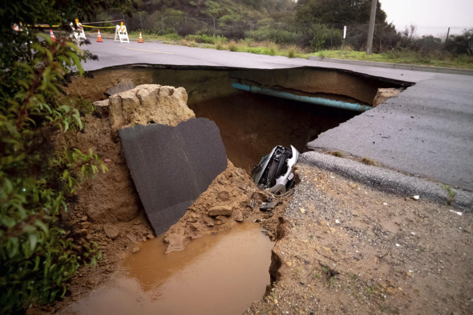 Cars remain in a large sinkhole along Iverson Road in Chatsworth, Calif., on Tuesday, Jan. 10, 2023. (David Crane/The Orange County Register via AP)