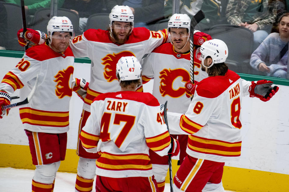 Calgary Flames player gather with Calgary Flames center Mikael Backlund (11) after he scored a goal during the third period of an NHL hockey game against the Dallas Stars, Friday, Nov. 24, 2023, in Dallas. (AP Photo/Emil T. Lippe)