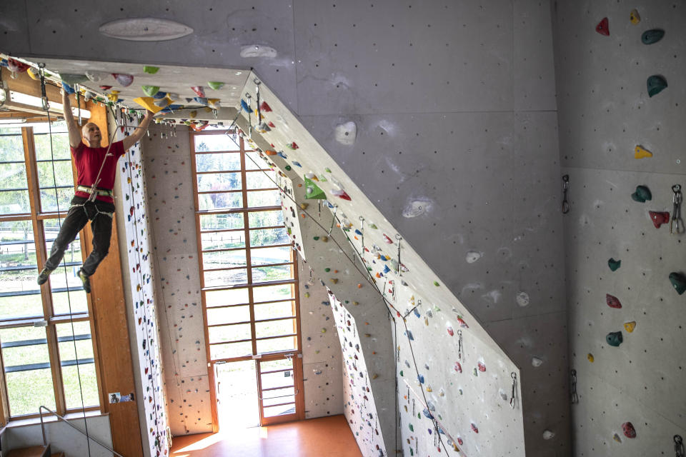 In this image take on Thursday, April 23, 2020 Giorgio Masserini, 61, hangs from the ceiling as he checks it inside the climbing gym 'Parco della Montagna', in Castione della Presolana, near Bergamo, northern Italy. His attitude is "Life is made of challenges". (AP Photo/Luca Bruno)