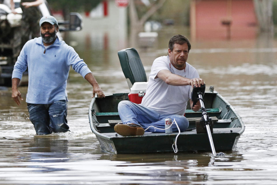 Marcus Morris steadies the boat as his neighbor Chris Sharp readies the trolling motor for another trip through their Pearl River flooded neighborhood in Jackson, Miss., Sunday, Feb. 16, 2020. Residents of Jackson braced Sunday for the possibility of catastrophic flooding in and around the Mississippi capital as the Pearl River rose precipitously after days of torrential rain. (AP Photo/Rogelio V. Solis)