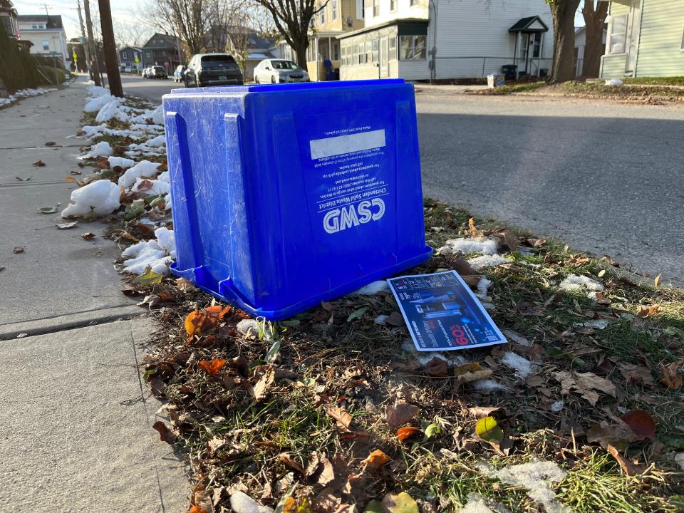 An overturned recycling bin sits on the curb on a residential street in Burlington. Thousands of households still use the lid-less blue bins which will soon be completely phased out with new city rules.