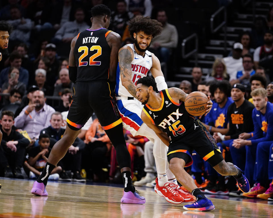 Phoenix Suns' Cameron Payne (15) gets around Detroit Pistons' Isaiah Livers (12) as Suns' Deandre Ayton (22) sets a screen during the first half of an NBA basketball game in Phoenix, Friday, Nov. 25, 2022. (AP Photo/Darryl Webb)