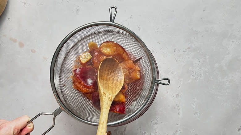 straining cooked plums over bowl