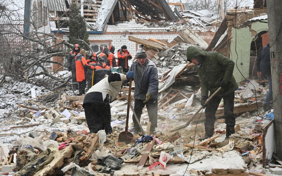 Locals clean up debris from a strike in Zmiiv, south of Kharkiv