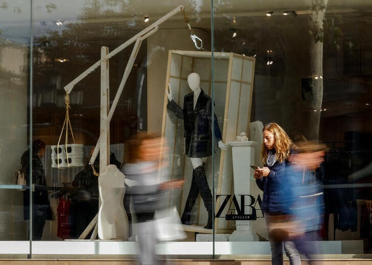 People walk past a Zara shop window at Passeig de Gracia in Barcelona