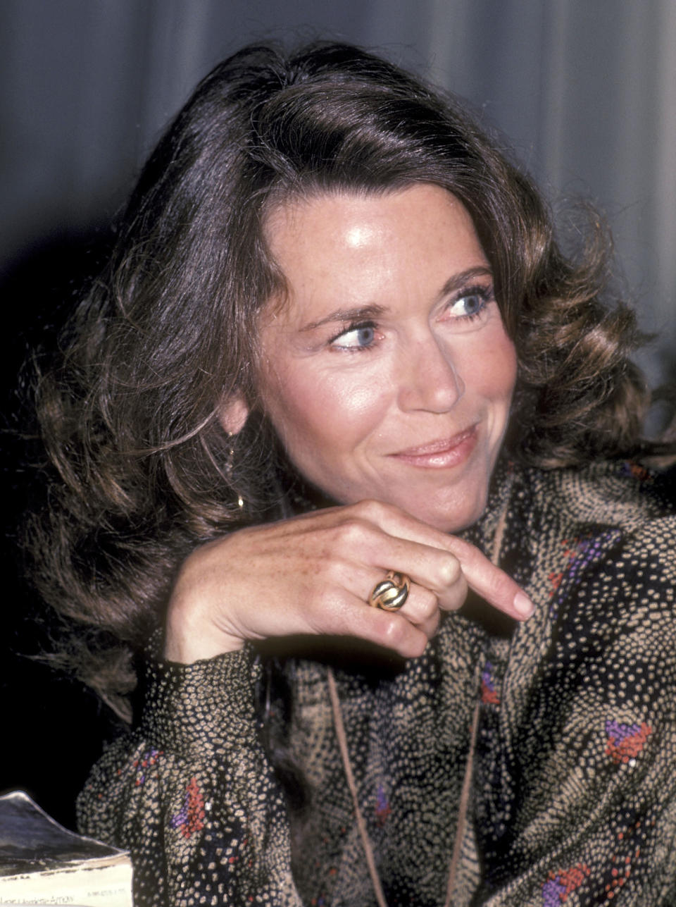 Close-up of Margaret Trudeau smiling with her chin resting on her hand, wearing a patterned top