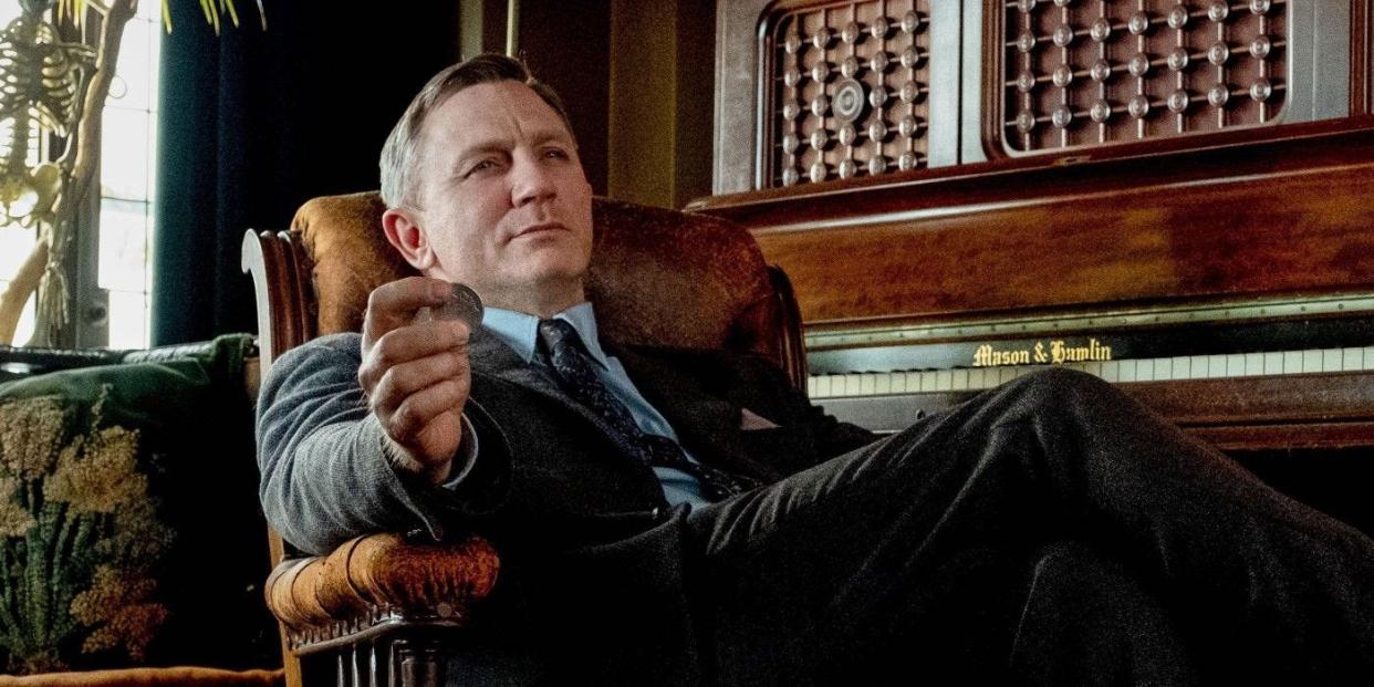 Daniel Craig in a chair holding a coin