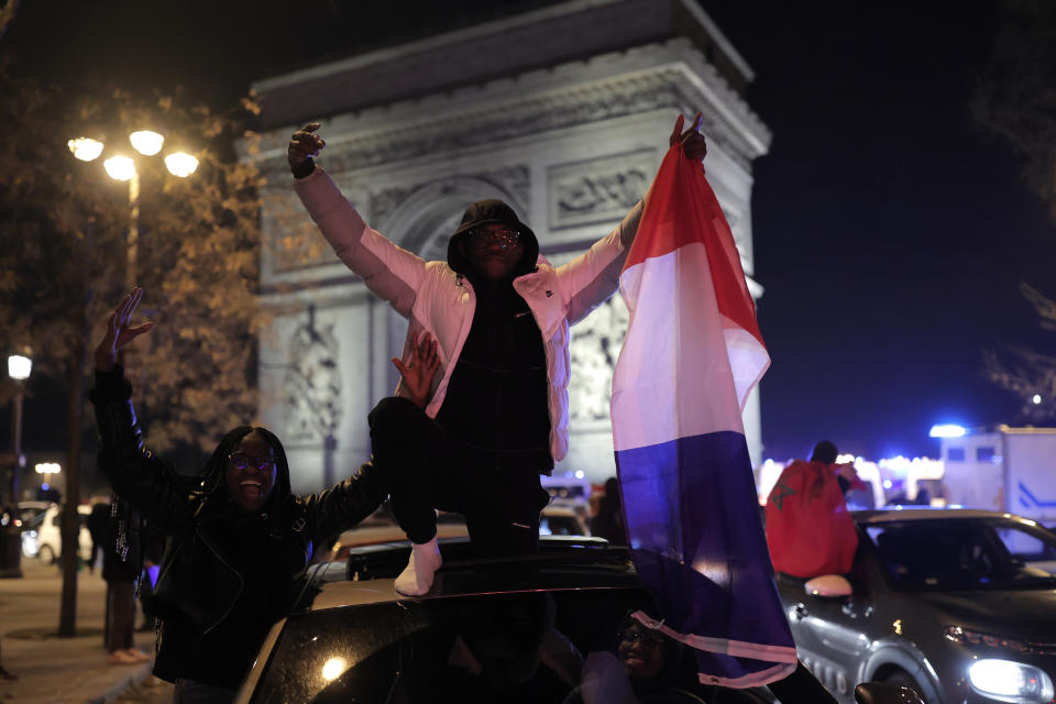 France supporters celebrate France's victory with French flags at the Arc de Triomphe after the World Cup semifinal soccer match between France and Morocco, Wednesday, Dec. 14, 2022 in Paris. France defeated Morocco 2-0 and will head into Sunday's title match against Argentina. (AP Photo/Lewis Joly)