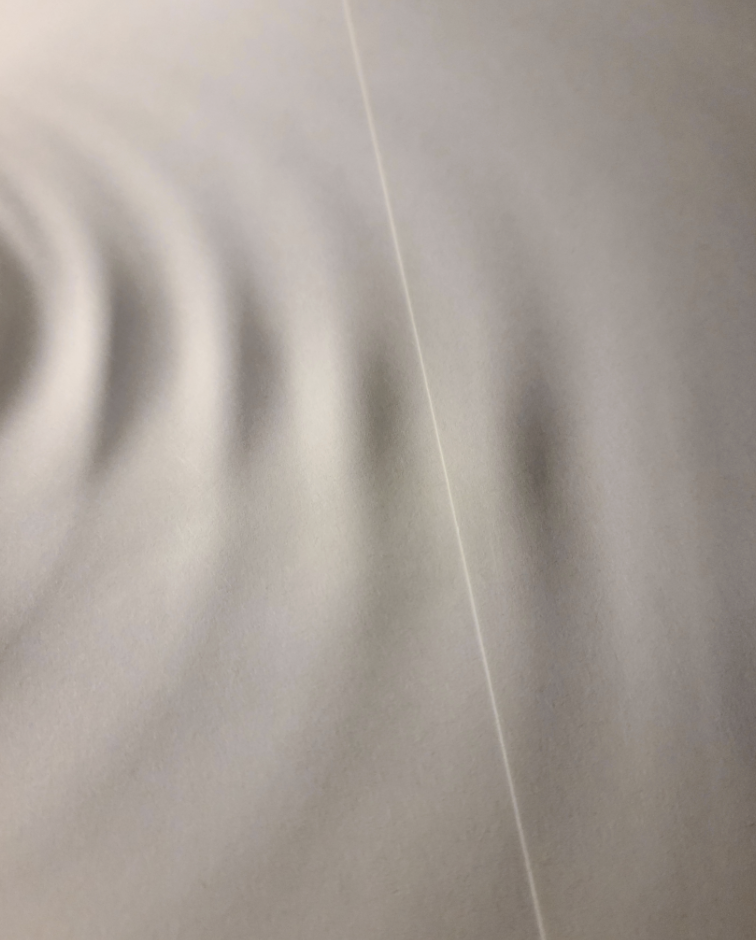 A visual of textured paper with soft, wavy patterns and a thin, straight line running vertically. No text or people are present