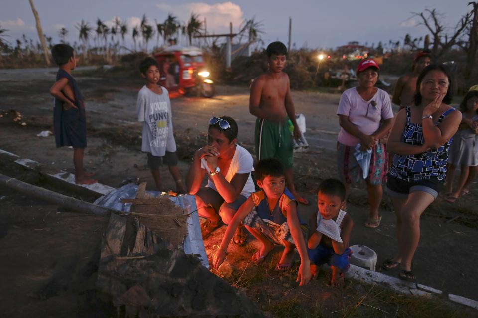 Relatives stand by candles lit on a mass grave by the side of a road south of Tacloban