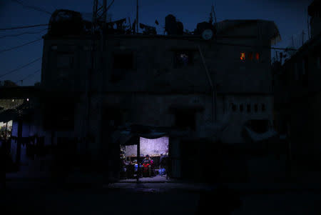 A Palestinian man sits as he sells vegetables in a makeshift shop lit with a lamp powered by a battery during a power cut in Beit Lahiya in the northern Gaza Strip. REUTERS/Mohammed Salem