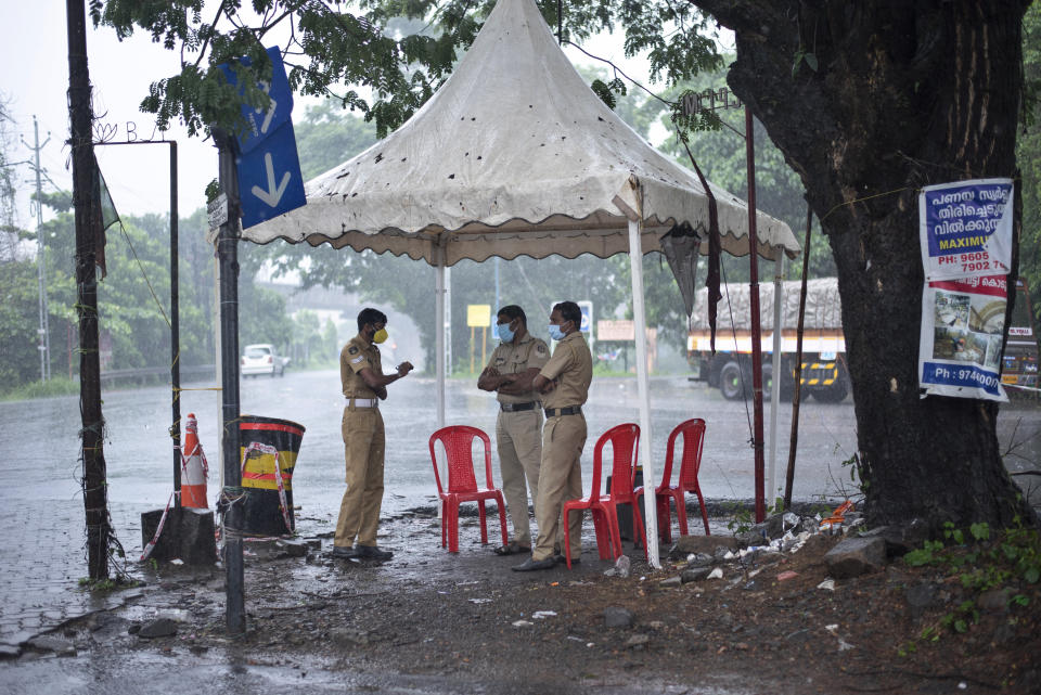 Policemen enforcing a lockdown to curb the spread of coronavirus stand beneath a rain shelter in Kochi, Kerala state, India, Sunday, May 16, 2021. A severe cyclone is roaring in the Arabian Sea off southwestern India with winds of up to 140 kilometers per hour (87 miles per hour), already causing heavy rains and flooding that have killed at least four people, officials said Sunday. (AP Photo/R S Iyer)