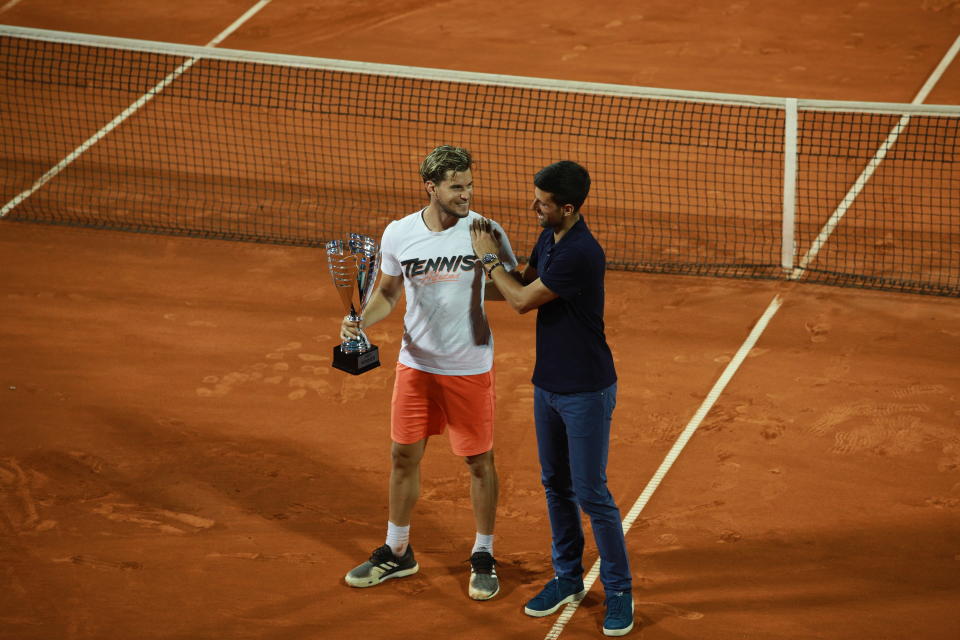 Dominic Thiem (pictured left) holds the trophy next to Novak Djokovic (pictured right) who congratulates him.