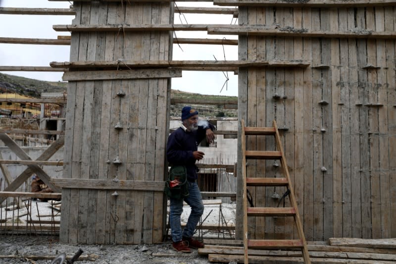 A Palestinian labourer smokes a cigarette at a construction site in the Israeli settlement of Ramat Givat Zeev in the Israeli-occupied West Bank