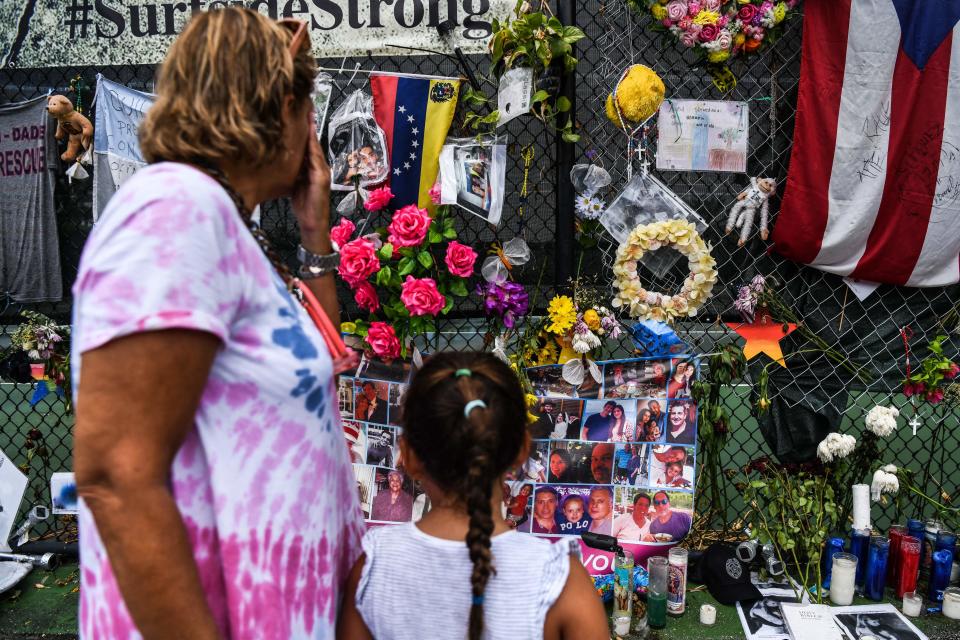 In this file photo taken on July 24, 2021, a woman cries as she visits a makeshift memorial where the partially collapsed Champlain Towers South building stood in Surfside, Florida. (Photo by CHANDAN KHANNA / AFP)