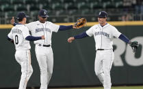 Seattle Mariners' Kyle Lewis, center, celebrates with teammates Sam Haggerty (0), and Dylan Moore, right, after the Mariners beat the Baltimore Orioles 5-2 in a baseball game, Tuesday, May 4, 2021, in Seattle. (AP Photo/Ted S. Warren)