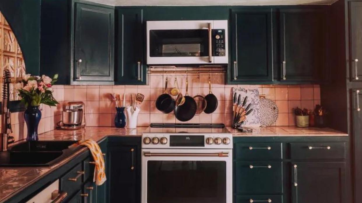  Dark green kitchen cabinets with blush pink walls. 