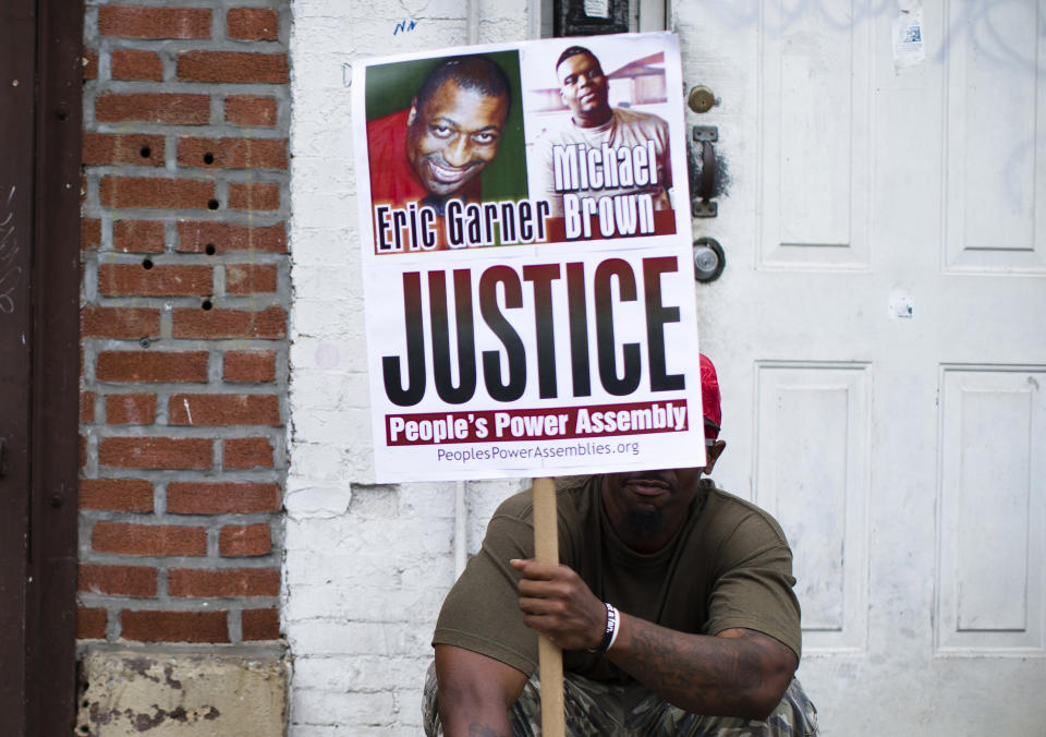 FILE - In this Aug. 23, 2014, file photo, a demonstrator holds a sign bearing the likeness of Eric Garner and Michael Brown before a march to protest the death of Garner, in the Staten Island borough of New York. A wave of police killings of young black men in 2014 prompted 24 states to quickly pass some type of law enforcement reform, but many declined to address the most glaring issue: police use of force. Six years later, only about a third of states have passed laws on the question. (AP Photo/John Minchillo, File)