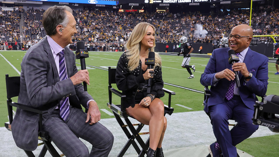 (L-R) NBC Sunday Night Football color commentator Cris Collinsworth, recording artist Carrie Underwood and NBC Sunday Night Football play-by-play announcer Mike Tirico talk before a game between the Pittsburgh Steelers and the Las Vegas Raiders at Allegiant Stadium on September 24, 2023 in Las Vegas, Nevada. The Steelers defeated the Raiders 23-18.