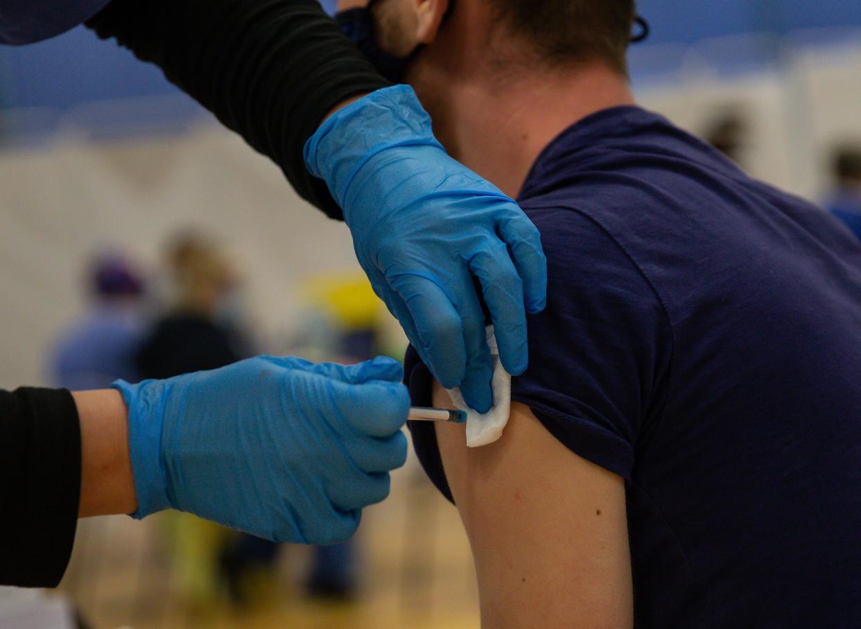 CWMBRAN, WALES - DECEMBER 29:  A general view of a NHS worker as he receives his first dose of the Pfizer/BioNTech vaccine in the waiting area for any adverse reactions on December 29, 2020 in Cwmbran, Wales. Various locations across United Kingdom were designated as covid-19 vaccine hubs. NHS staff, over-80s, will be among the first to receive the Pfizer/BioNTech vaccine, which recently received approval from the country's health authorities. It is anticipated that the Oxford University Vaccine will be approved within the next few days. (Photo by Huw Fairclough/Getty Images)