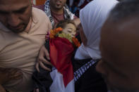 Ramallah governor Laila Ghannam, with a white scarf, carries the body of 2 1/2 year old Palestinian toddler Mohammed al-Tamimi upon his arrival at the Palestine Medical Complex, in the West Bank city of Ramallah, Monday, June 5, 2023. The Palestinian toddler who was shot by Israeli troops in the occupied West Bank last week died of his wounds on Monday, Israeli hospital officials said. (AP Photo/Nasser Nasser)