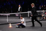 A protester lights a fire on the court on day one of the Laver Cup on day one of the Laver Cup at the O2 Arena in London, Friday Sept. 23, 2022. (John Walton/PA via AP)