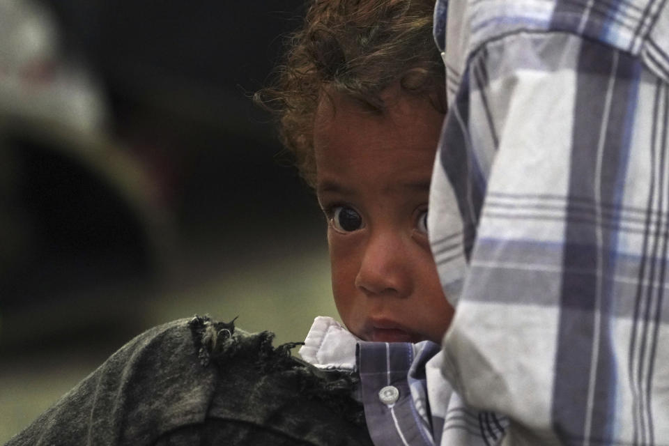 A child is held by an adult amid a migrant group breaking up camp after sleeping on the street in Huixtla, Chiapas state, Mexico, at daybreak Tuesday, Oct. 26, 2021, as they use the day to rest during their ongoing trek by foot toward the U.S. (AP Photo/Marco Ugarte)