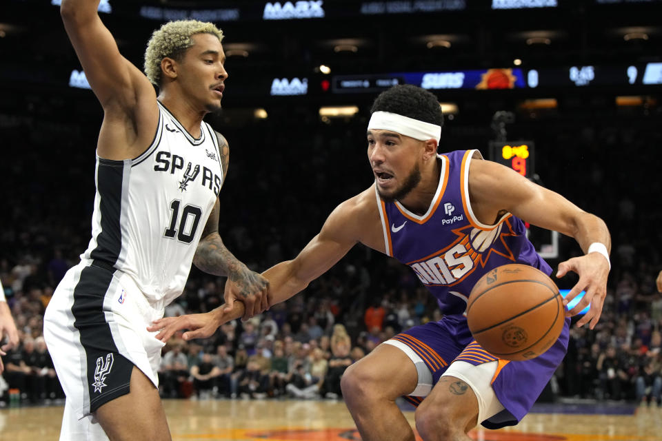 Phoenix Suns guard Devin Booker is defended by San Antonio Spurs forward Jeremy Sochan (10) during the first half of an NBA basketball game Thursday, Nov 2, 2023, in Phoenix. (AP Photo/Rick Scuteri)