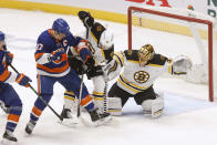 New York Islanders' Anders Lee (27) and Boston Bruins' Jeremy Lauzon (55) battle for possession as Bruins goalie Tuukka Rask (40), of Finland, defends the net during the first period of an NHL hockey game Monday, Jan. 18, 2021, in Uniondale, N.Y. (AP Photo/Jason DeCrow)