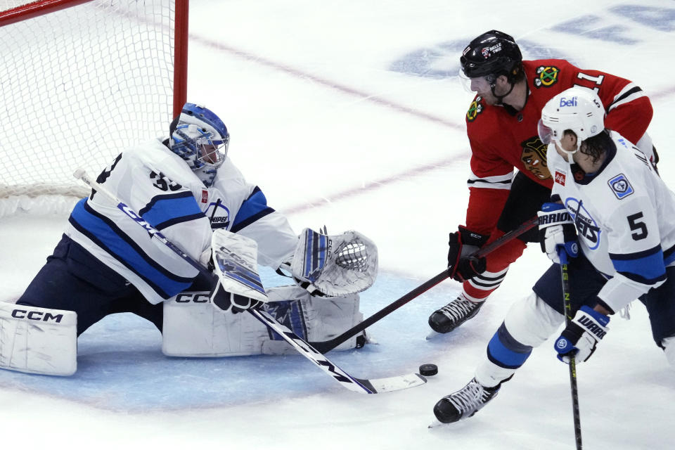 Winnipeg Jets goaltender David Rittich makes a save against Chicago Blackhawks right wing Taylor Raddysh (11) during the third period of an NHL hockey game in Chicago, Friday, Dec. 9, 2022. The Jets won 3-1. (AP Photo/Nam Y. Huh)