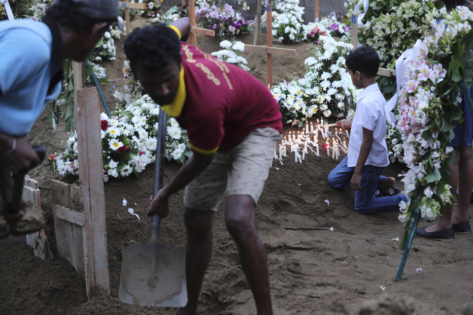 A boy lights a candle after the funeral service of Dhami Brandy, 13, who was killed during Easter Sunday's bomb blast at St. Sebastian Church, in Negombo, Sri Lanka Thursday, April 25, 2019. The U.S. Embassy in Sri Lanka warned Thursday that places of worship could be targeted for militant attacks over the coming weekend, as police searched for more suspects in the Islamic State-claimed Easter suicide bombings that killed over 350 people. (AP Photo/Manish Swarup)