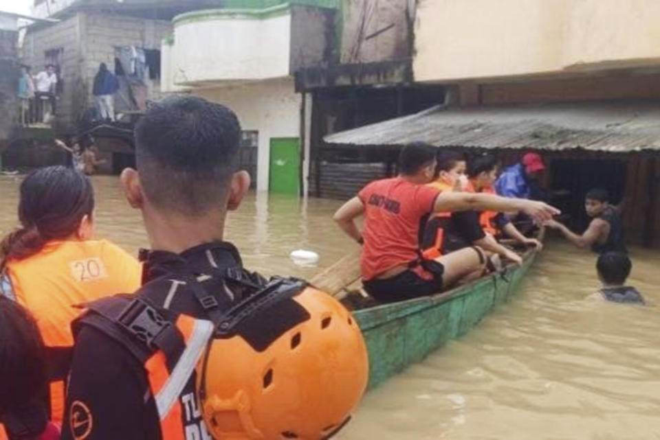 In this handout photo provided by the Philippine Coast Guard, rescuers evacuate residents at a flooded village in Tuguegarao city, Cagayan province, northern Philippines on Sunday Oct. 30, 2022. Victims of a huge mudslide set off by a storm in a coastal Philippine village that had once been devastated by a killer tsunami mistakenly thought a tidal wave was coming and ran to higher ground toward a mountain and were buried alive, an official said Sunday. (Philippine Coast Guard via AP)